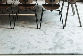 Illustration - Ihr Experte für schönes Wohnen - Ein graumelierter Teppich liegt im Esszimmer unter dem Tisch.