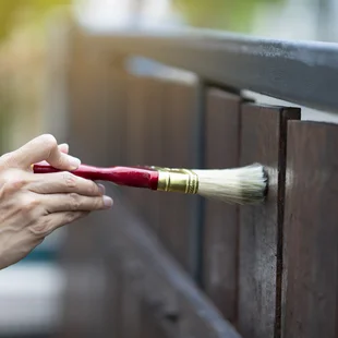 Gartenzaun - ufbringen eines Schutzlacks auf ein Holzstruktur-, DIY- und Reparaturhausausrüstungskonzept Farbe Holzschutz