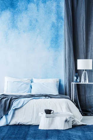 Illustration - Ihr Experte für schönes Wohnen - Ein gemütlichen Bett mit blauer Decke steht vor einer Wand Ombre in Schlafzimmer Innenraum 