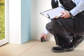 Aufmass vor Ort - Decor-Union Service 036a Bodenleger vermisst mit einem Lasermessgerät den Raum für einen Bodebelag aus.
