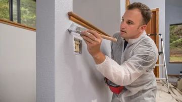 Professionelle kommerzielle, Anstreicher, Wand Malerei mit Pinsel drinnen im Zimmer des Hauses